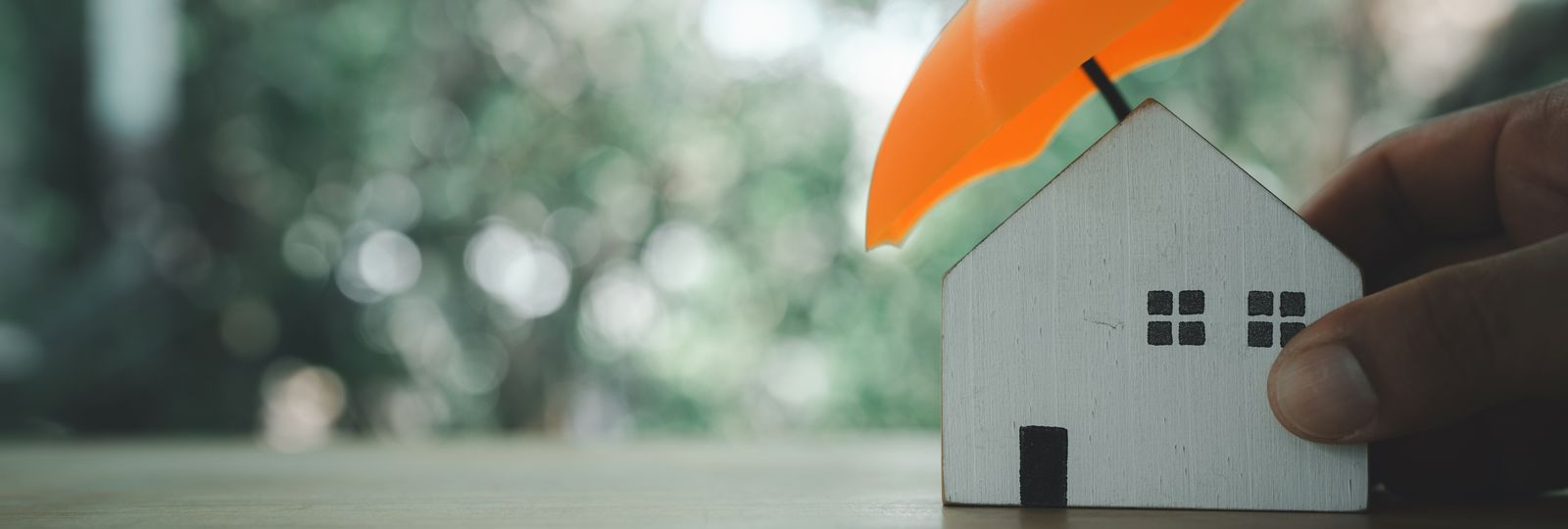 Un parapluie abritant une petite maison en bois
